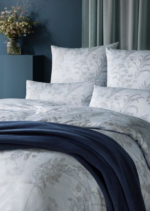 Florale Bettwäsche Elke in hellem Grau-Weiß mit feinem Pflanzenmuster auf modernem Bett, kombiniert mit dunkelblauer Wohndecke Trevi 